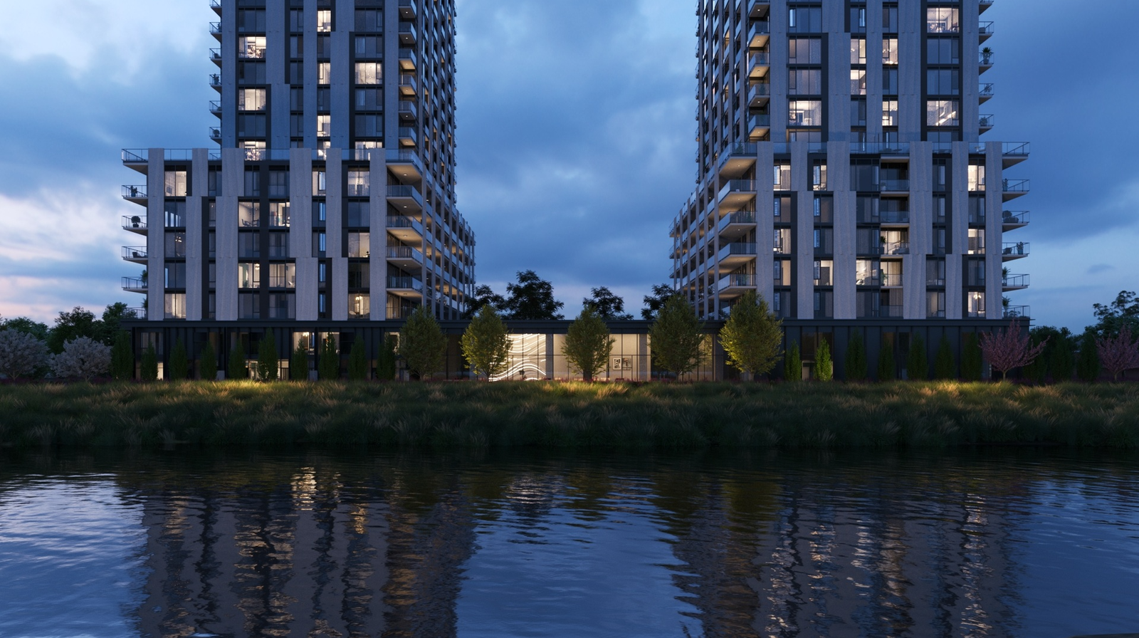 Twin residential towers beside a river at dusk